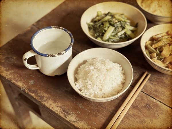80年代老旧餐桌上的搪瓷杯和饭菜